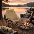 CampComfort foldable moon chair set up by a cozy lakeside campfire