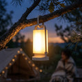 LuminaSolar vintage gold lantern hanging from a pine branch at twilight, premium outdoor camping lifestyle detail