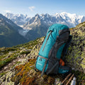 ApexPeak 70L trekking backpack resting on a mossy rock in the mountains