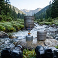 ApexTi Pure Titanium Cookware Set on burner boiling water in scenic outdoor camping lifestyle scene