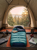 AeroDown™ Mummy Sleeping Bag laid out inside a cozy open tent looking out onto a pine forest at sunrise